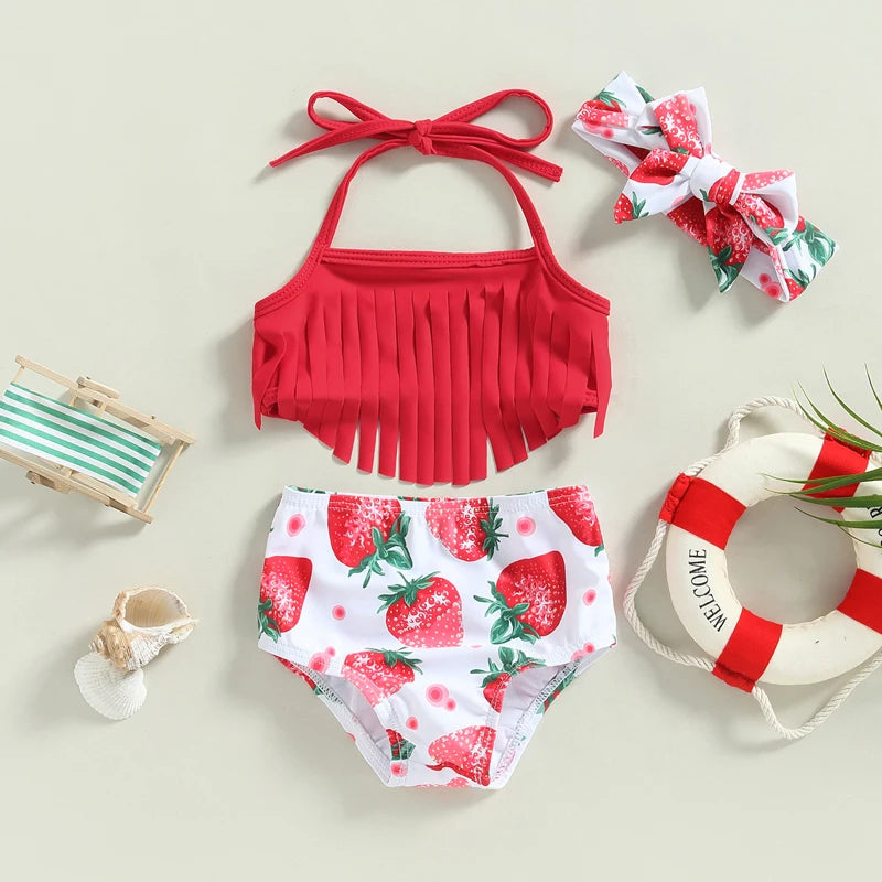 Red bikini top with fringes, strawberry-patterned shorts, and matching headband on a light background.