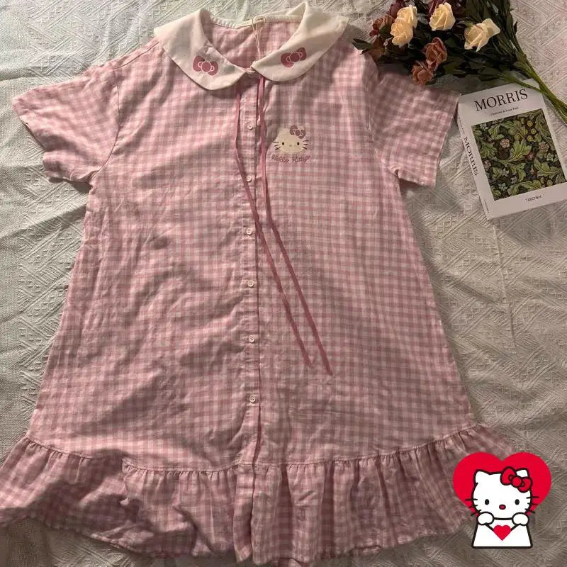 Pink checkered dress with Hello Kitty design on a bed with a magazine and flowers.