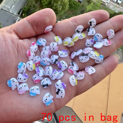 Hand holding small Hello Kitty figurines with a blurred outdoor background