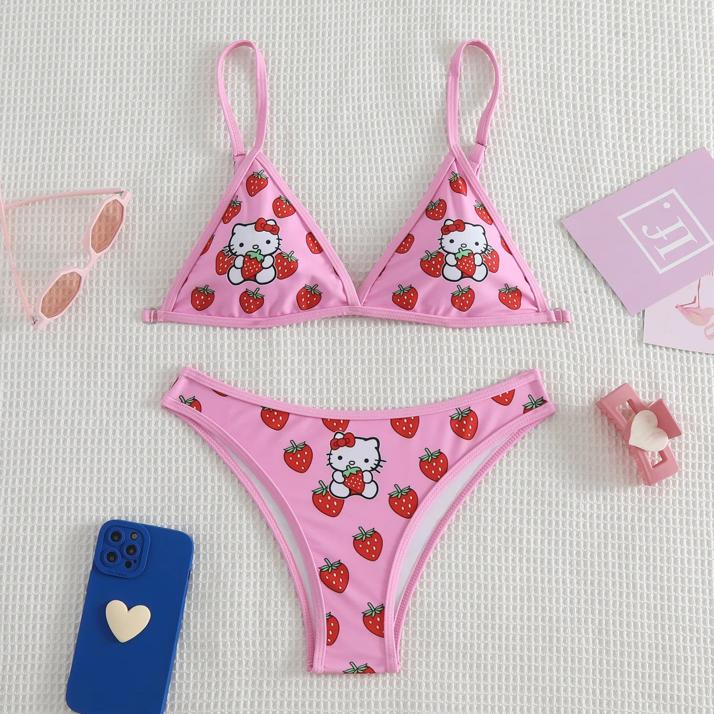 Pink bikini set with Hello Kitty and strawberry pattern on a light gray background