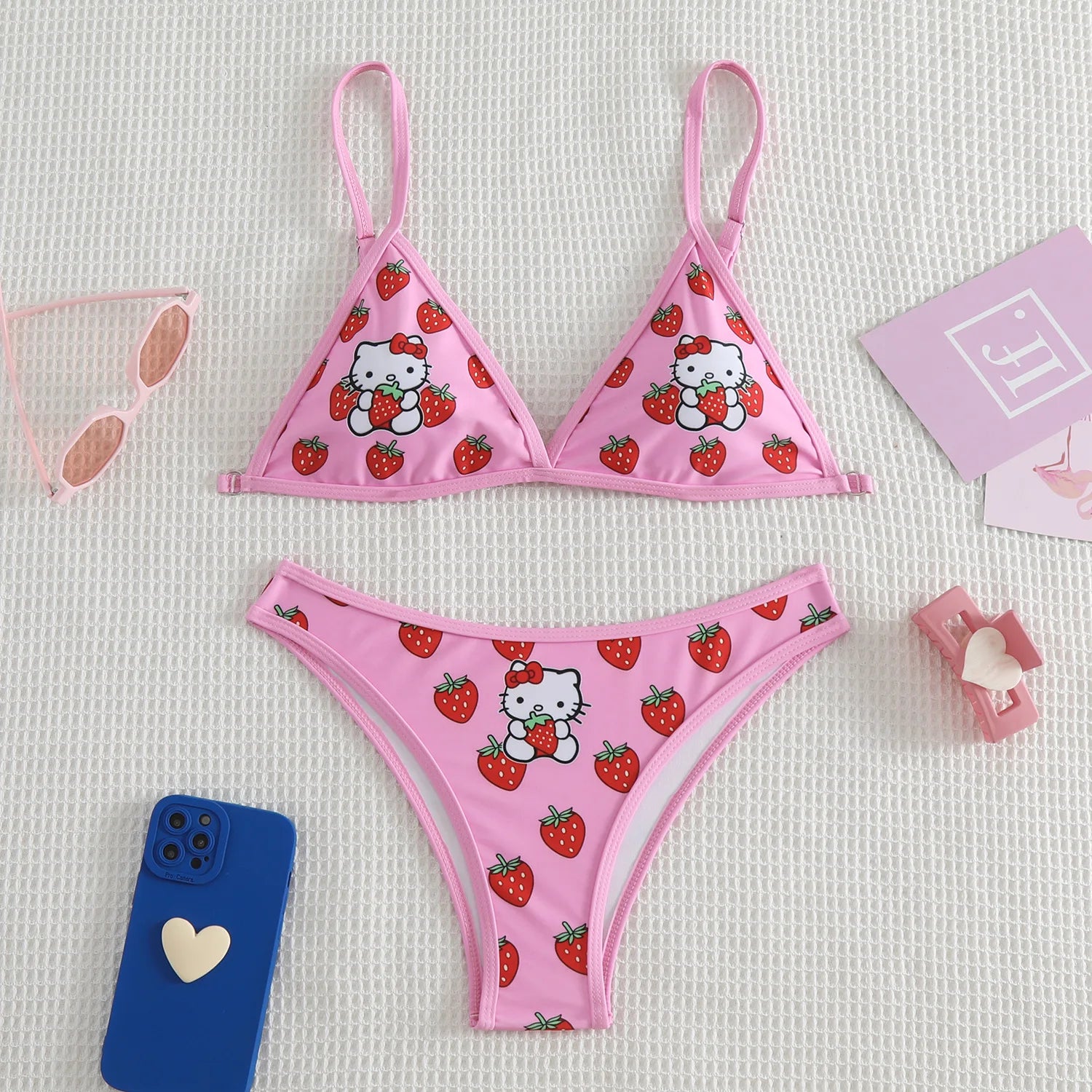 Pink bikini set with Hello Kitty and strawberry pattern on a light gray background