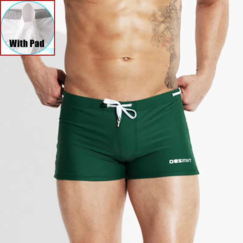 Green swim shorts with a white drawstring on a plain background