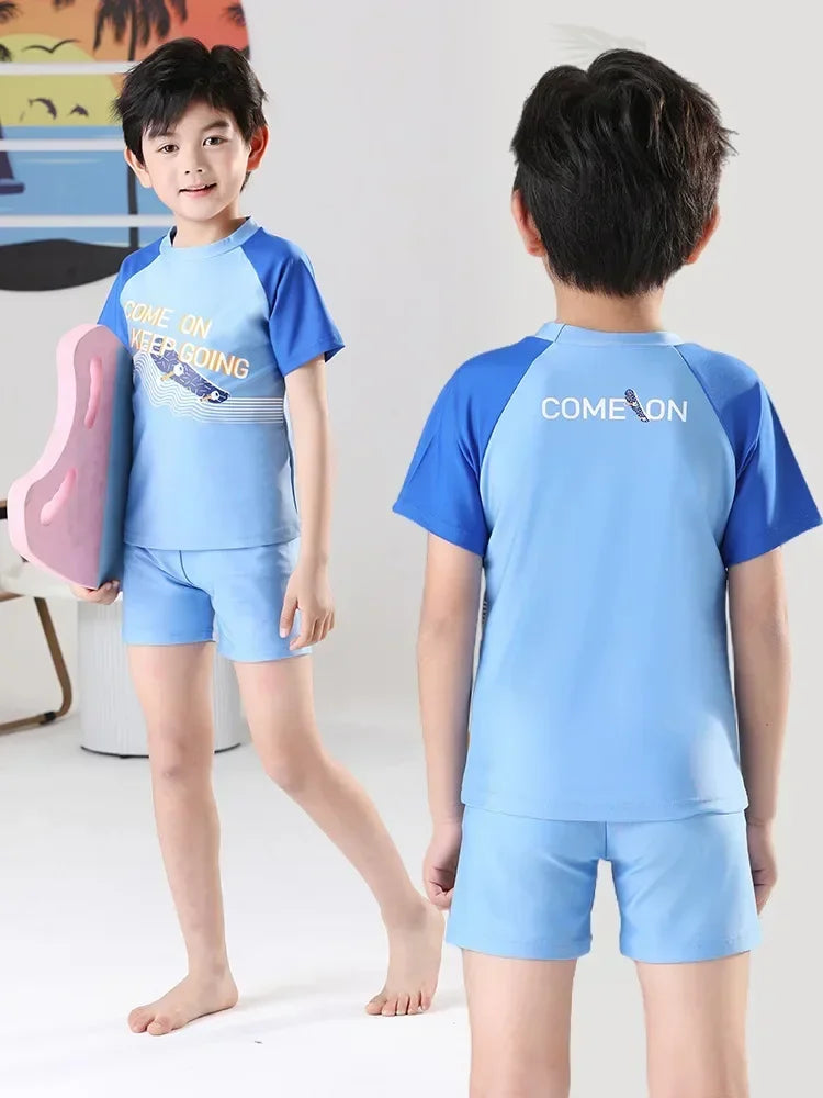 Child wearing a blue and navy swimsuit with 'COME ON' text, holding a pink object.