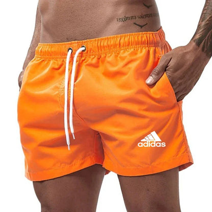 Orange Adidas shorts worn by a person on a white background