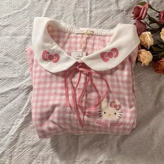 Pink checkered shirt with Hello Kitty design on a textured surface with flowers.
