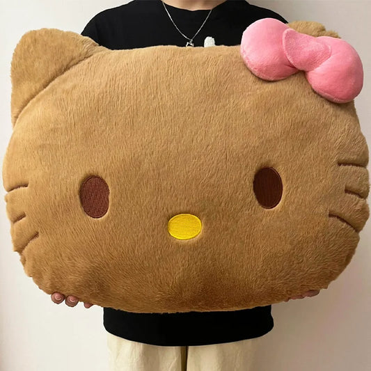 Large plush pillow shaped like a cat face with a pink bow held by a person.