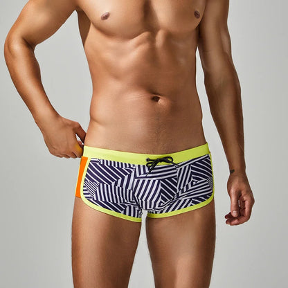 Man wearing striped swim shorts with a colorful waistband on a plain background