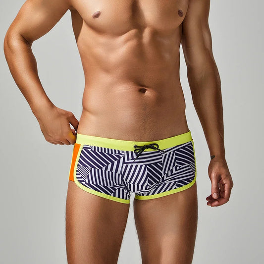 Man wearing striped swim shorts with a colorful waistband on a plain background
