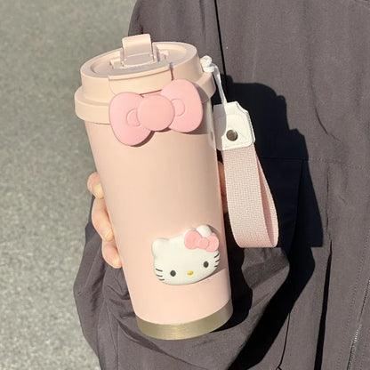 Pink water bottle with Hello Kitty design held by a person wearing a gray jacket.