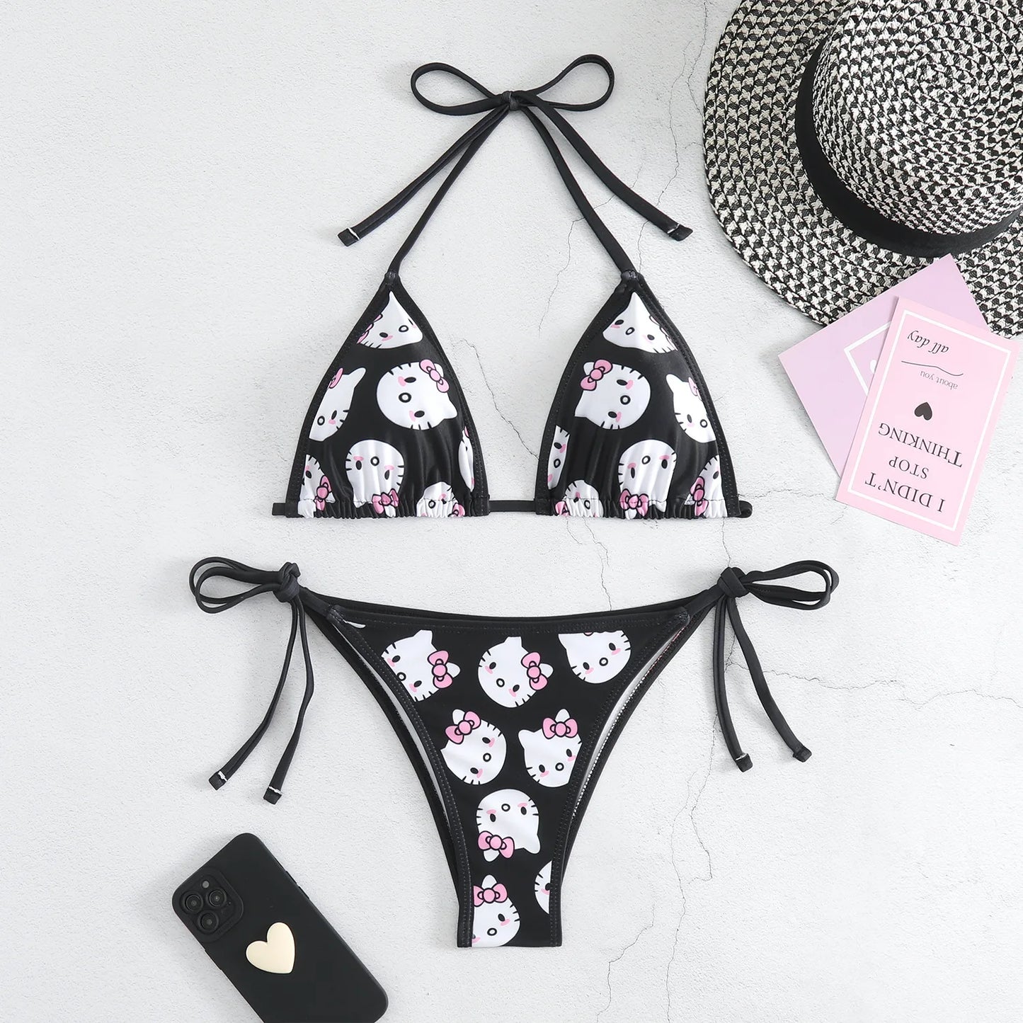 Black bikini with white cat print on a light gray background