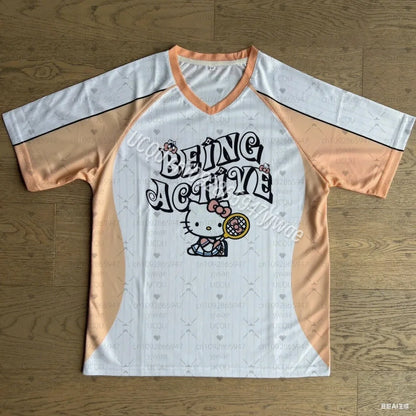 Baseball-style shirt with 'Being Active' text and Hello Kitty graphic on a wooden surface