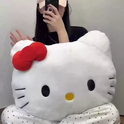 Person holding a large white plush toy pillow shaped like a cat face with a red bow.