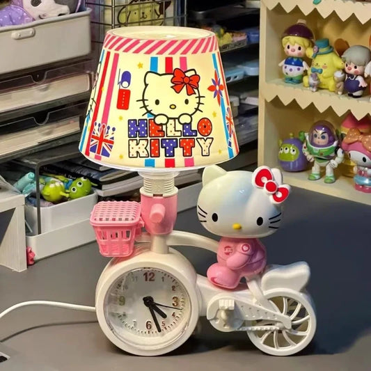 Hello Kitty-themed lamp with a bicycle design and clock on a shelf with toys in the background.