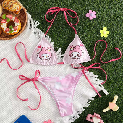 Pink bikini set with cartoon character design on grass with donuts and flowers.