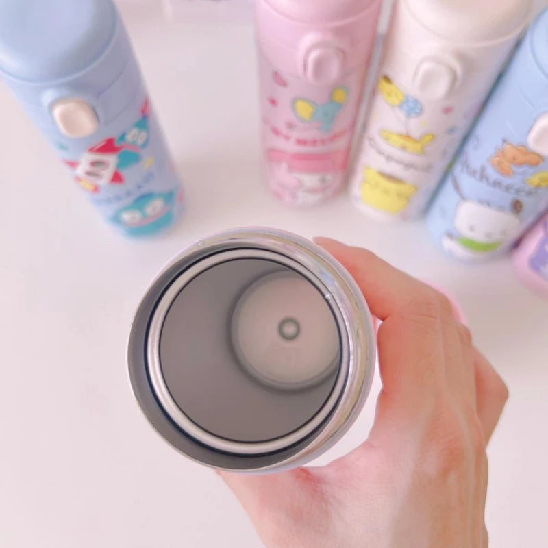 Hand holding a white tumbler with colorful cartoon designs on a white background