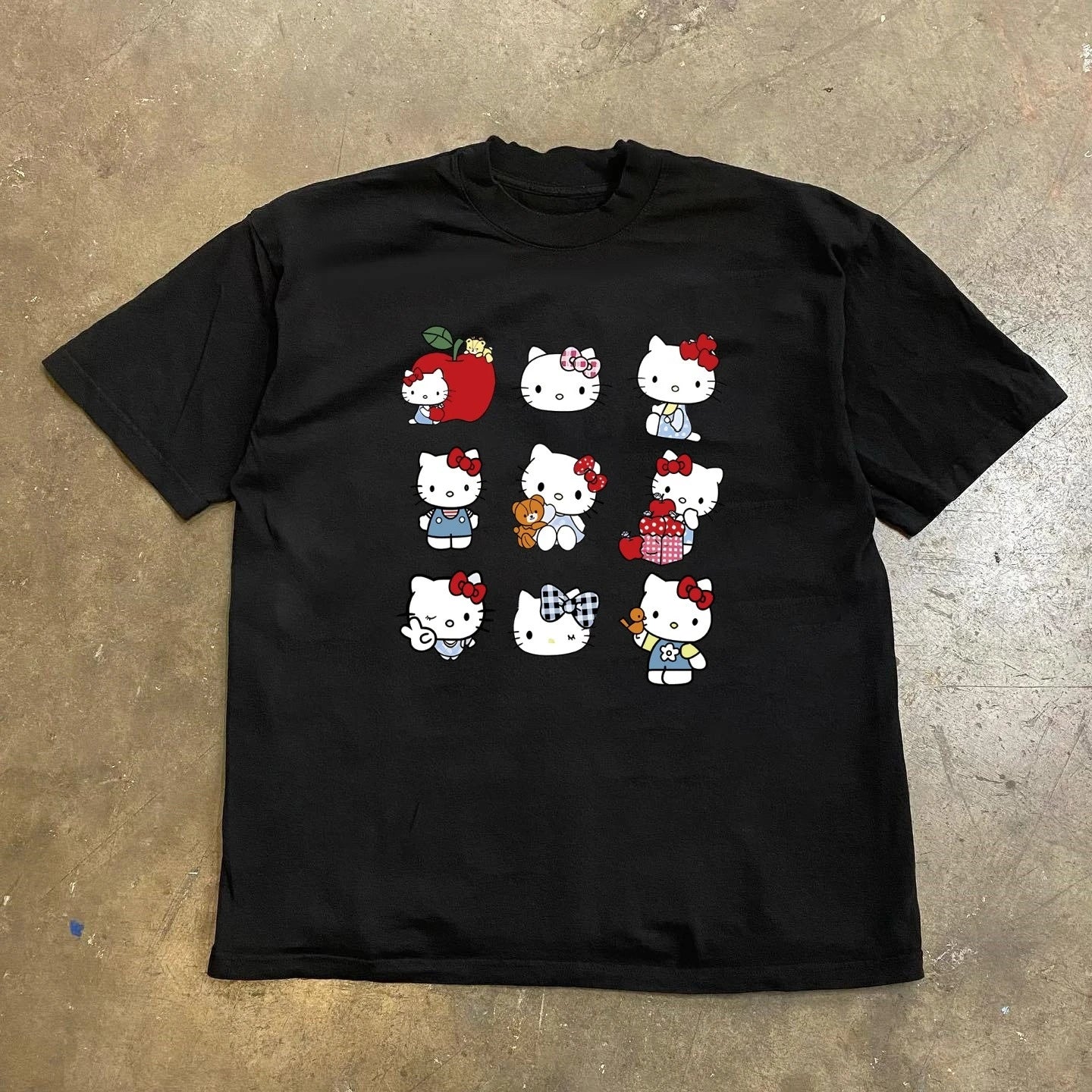 Black t-shirt with cartoon character design on a concrete floor