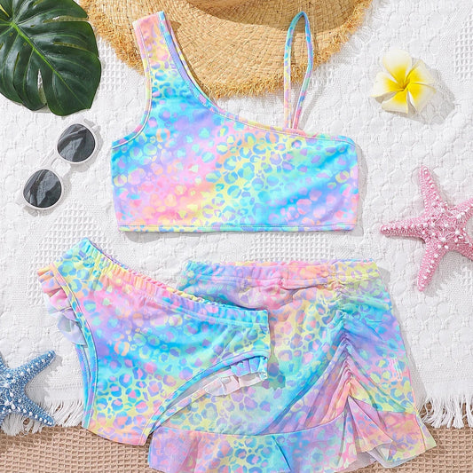 Colorful tie-dye bikini set with a straw hat, sunglasses, and flowers on a white background.
