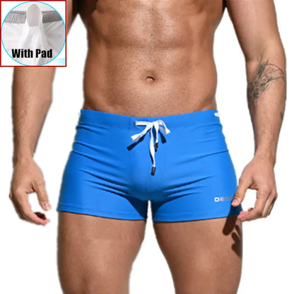 Blue swim shorts with a white drawstring on a plain background