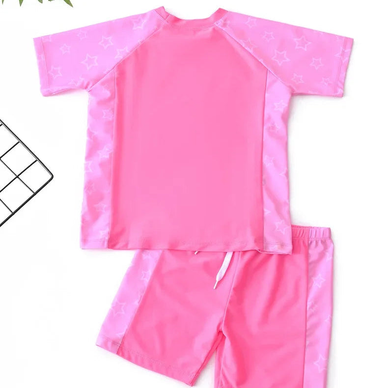 Pink rash guard and shorts set on a white background with a leaf decoration.