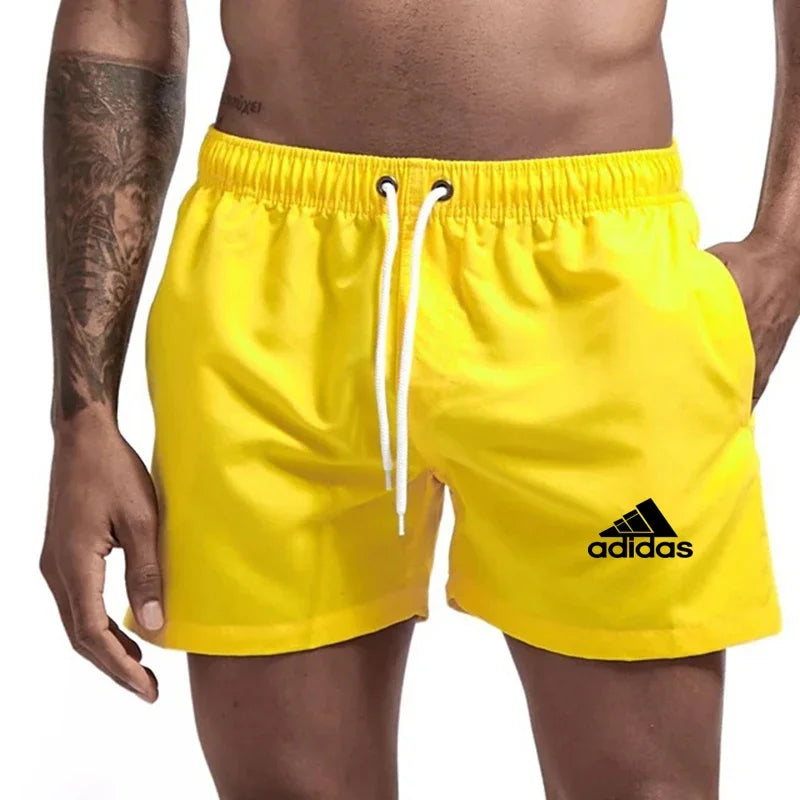 Yellow Adidas shorts worn by a person on a plain background