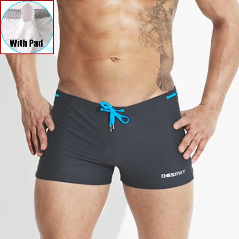 Man wearing black swim shorts with blue drawstring, Desmi brand visible, inset showing swim shorts with pad.