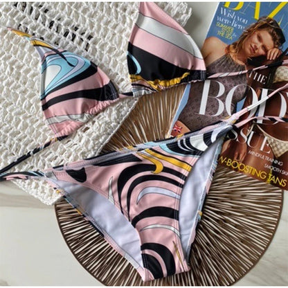Colorful bikini set on a textured surface with a magazine underneath