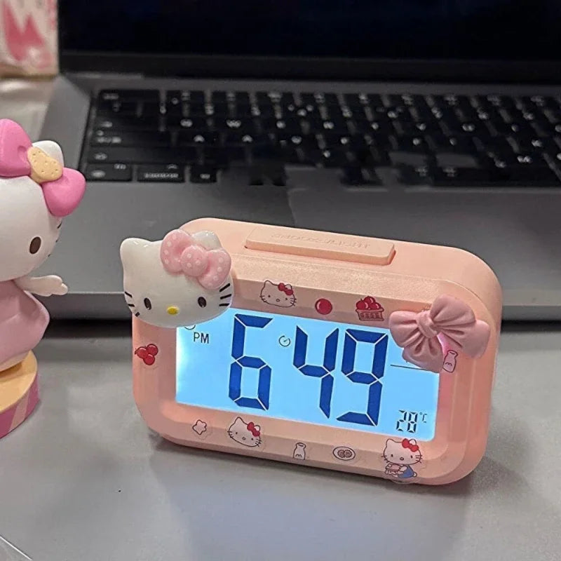 Hello Kitty-themed digital clock on a desk with a laptop in the background