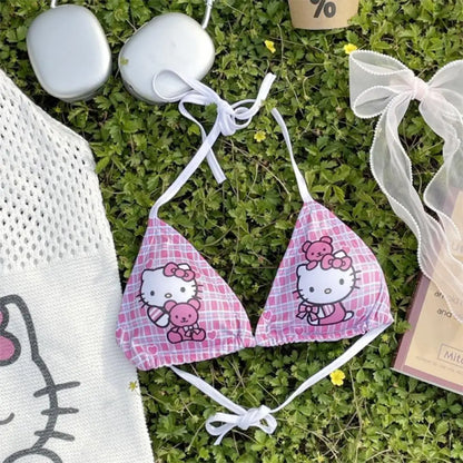 Hello Kitty bikini set on grass with a white bag and pink box in the background