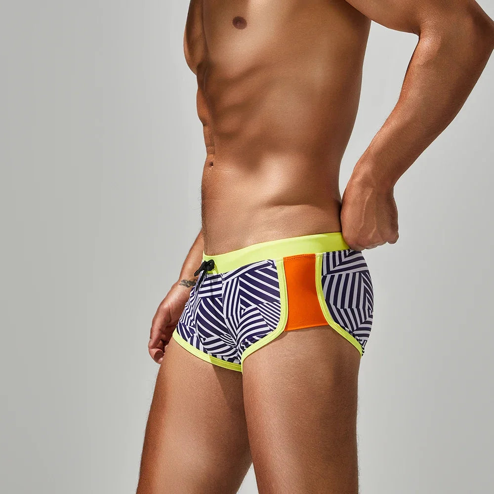Person wearing a colorful patterned swim brief on a gray background
