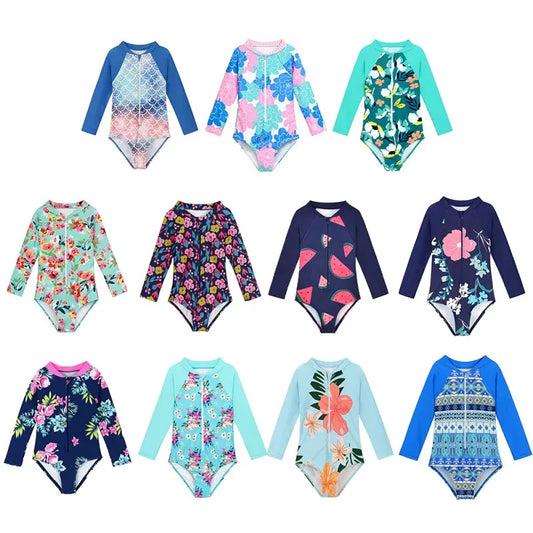 Collection of colorful children's swimsuits with various patterns on a white background