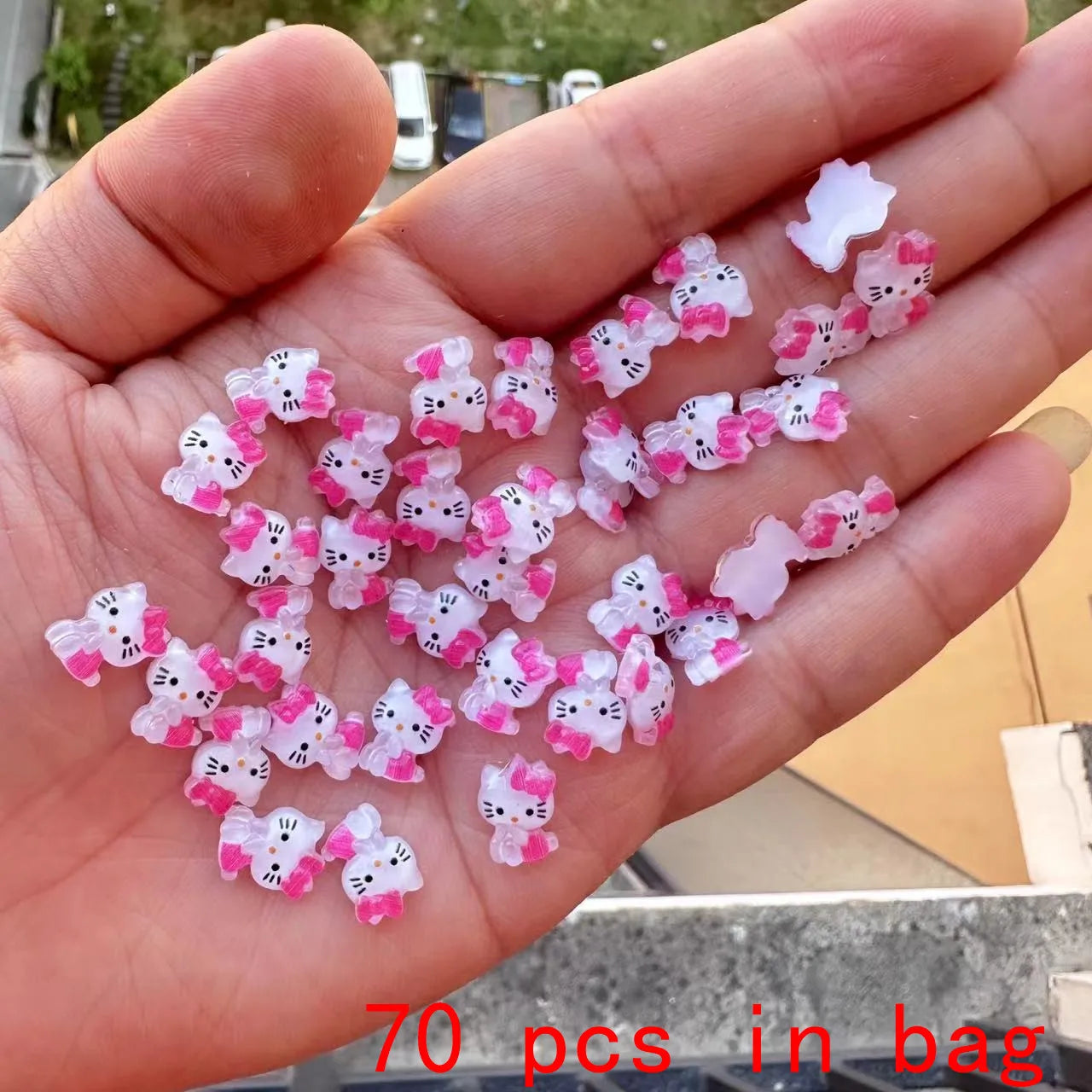 Hand holding a small collection of Hello Kitty-themed decorative items with '70 pcs in bag' text.