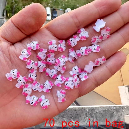 Hand holding a small collection of Hello Kitty-themed decorative items with '70 pcs in bag' text.