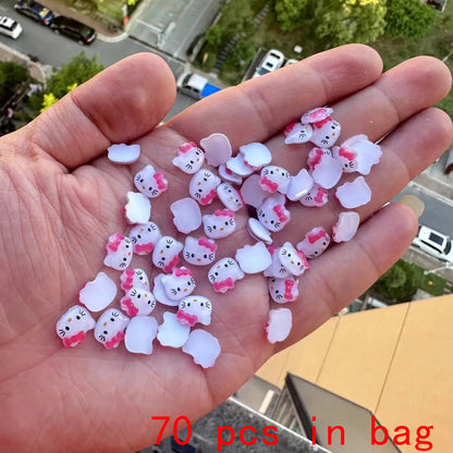 Hand holding small Hello Kitty figurines with a cityscape in the background
