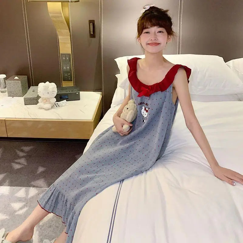 Woman in a blue dress with red collar sitting on a bed holding a teddy bear.