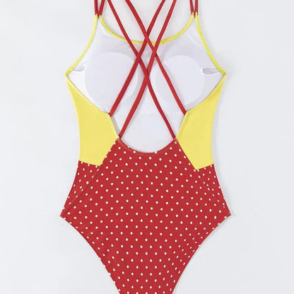 One-piece swimsuit with red polka dot pattern and yellow and red criss-cross straps on a white background