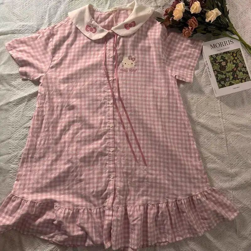 Pink checkered dress with Hello Kitty design on a bed with a magazine and flowers.