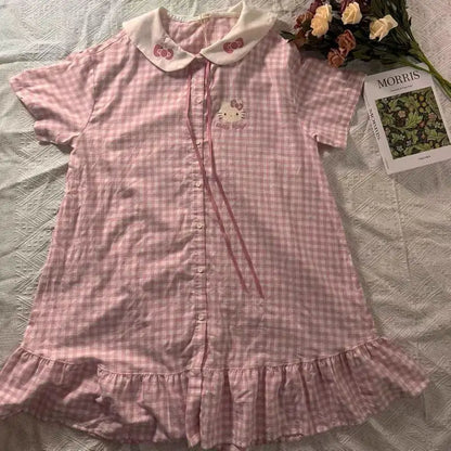 Pink checkered dress with Hello Kitty design on a bed with a magazine and flowers.