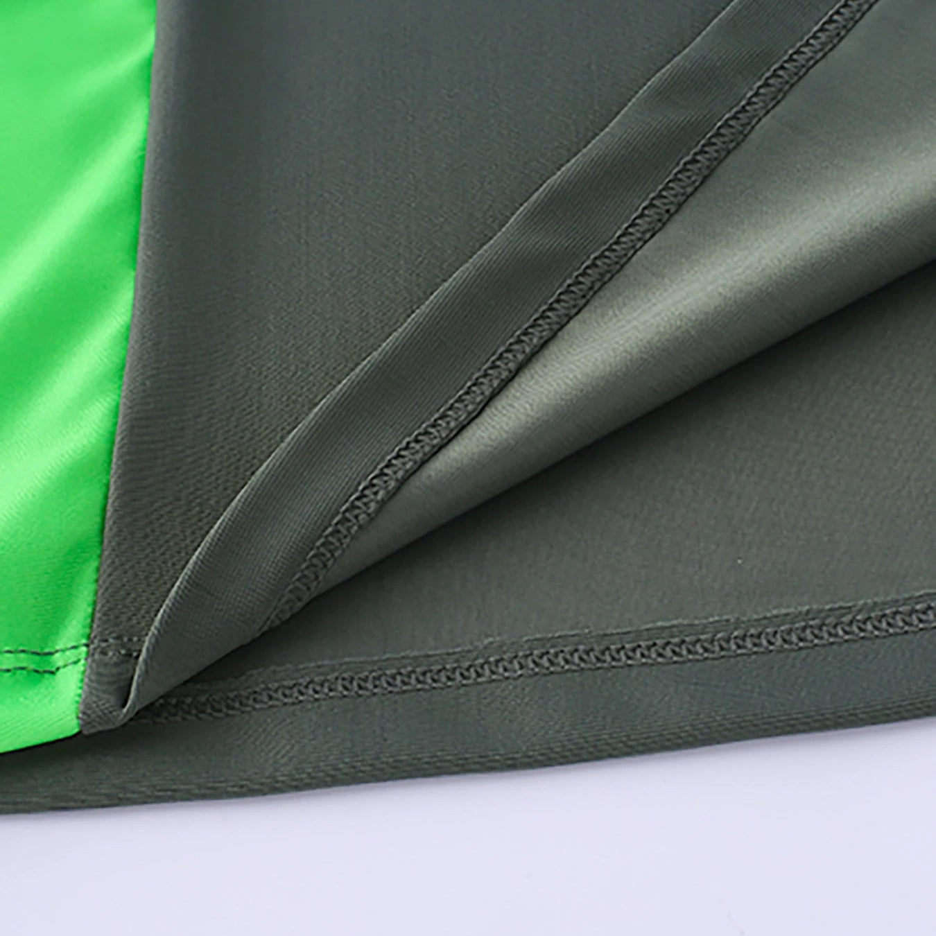 Close-up of green and gray fabric with visible stitching on a white background