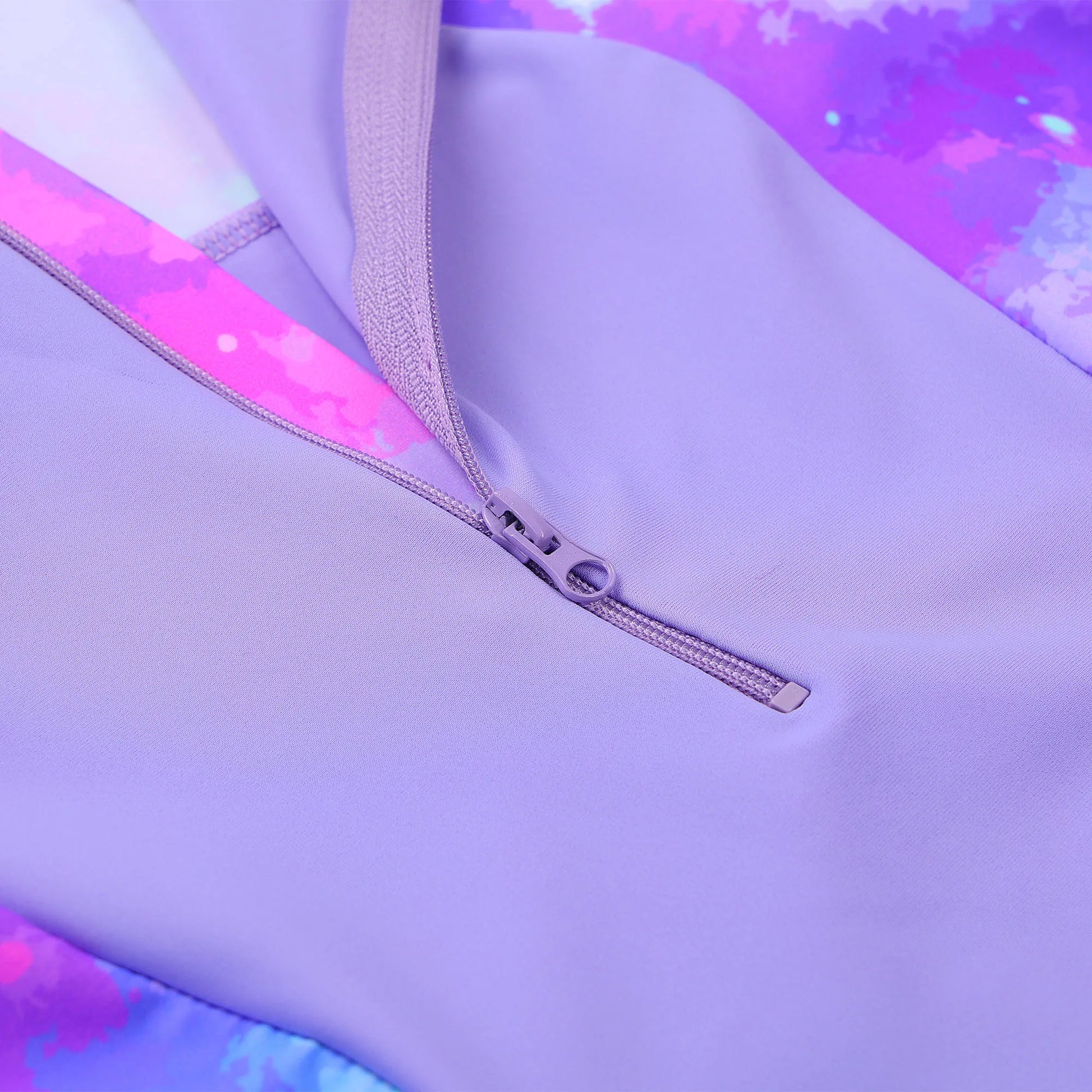 Close-up of a purple garment with a zipper, featuring a tie-dye pattern in the background.