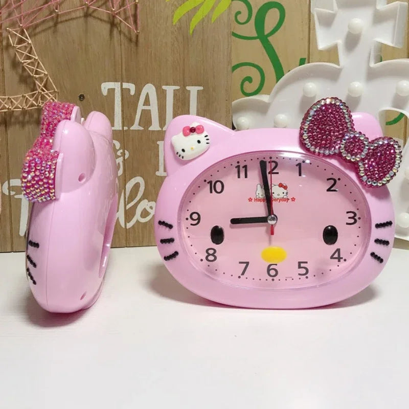 Pink Hello Kitty alarm clock with bow and ears on a white surface.