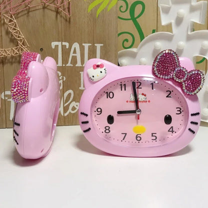 Pink Hello Kitty alarm clock with bow and ears on a white surface.