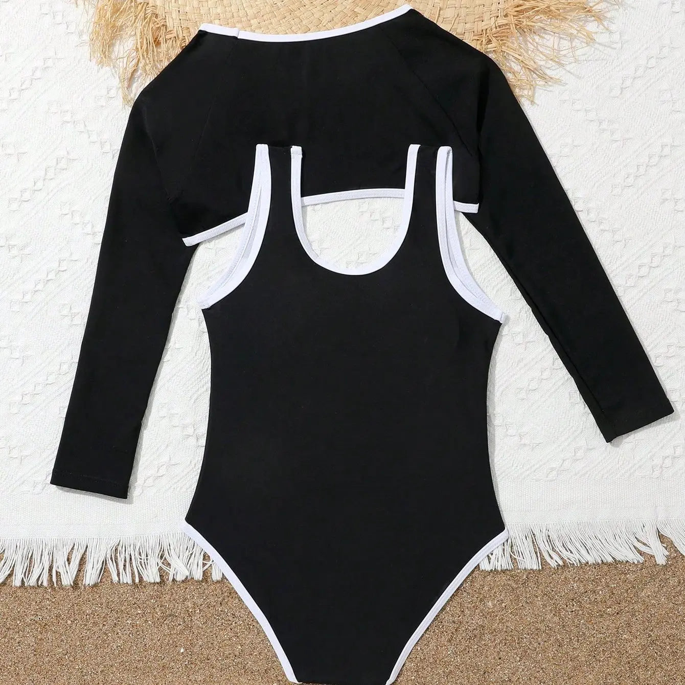 Black swimsuit with long sleeves and white trim on a textured surface