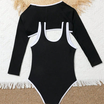 Black swimsuit with long sleeves and white trim on a textured surface