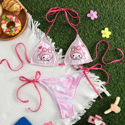 Pink bikini set with cartoon character design on grass with donuts and flowers.