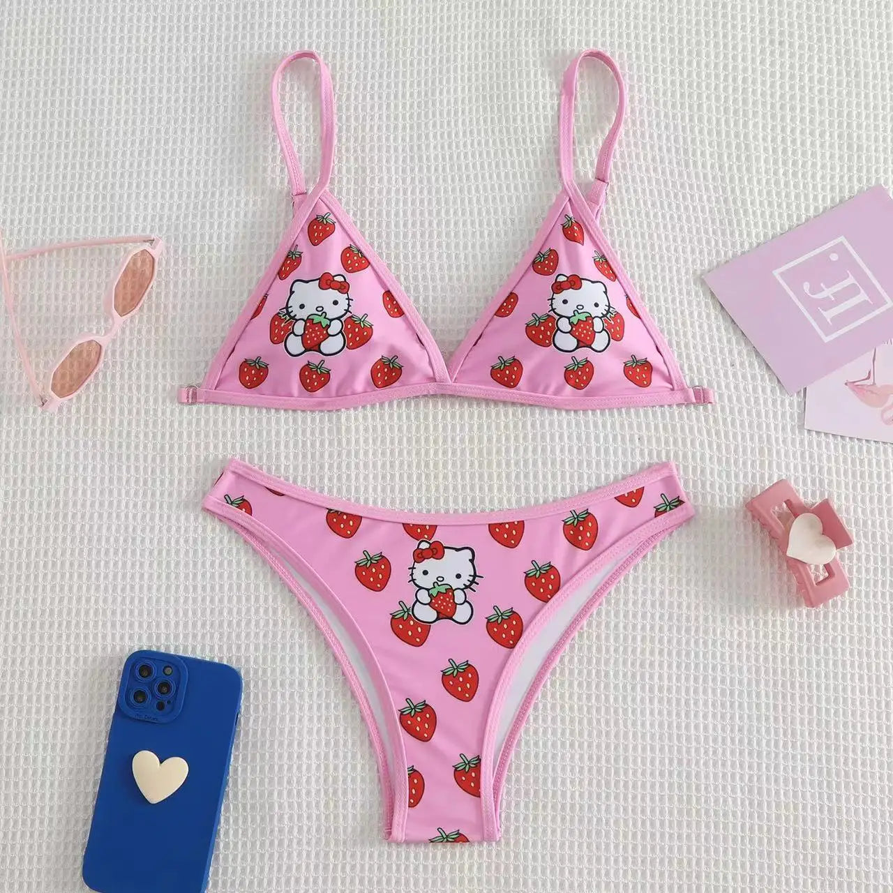 Pink bikini set with Hello Kitty and strawberry pattern on a light gray background