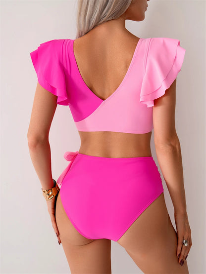 Woman wearing a bright pink two-piece swimsuit with ruffled sleeves on a plain background