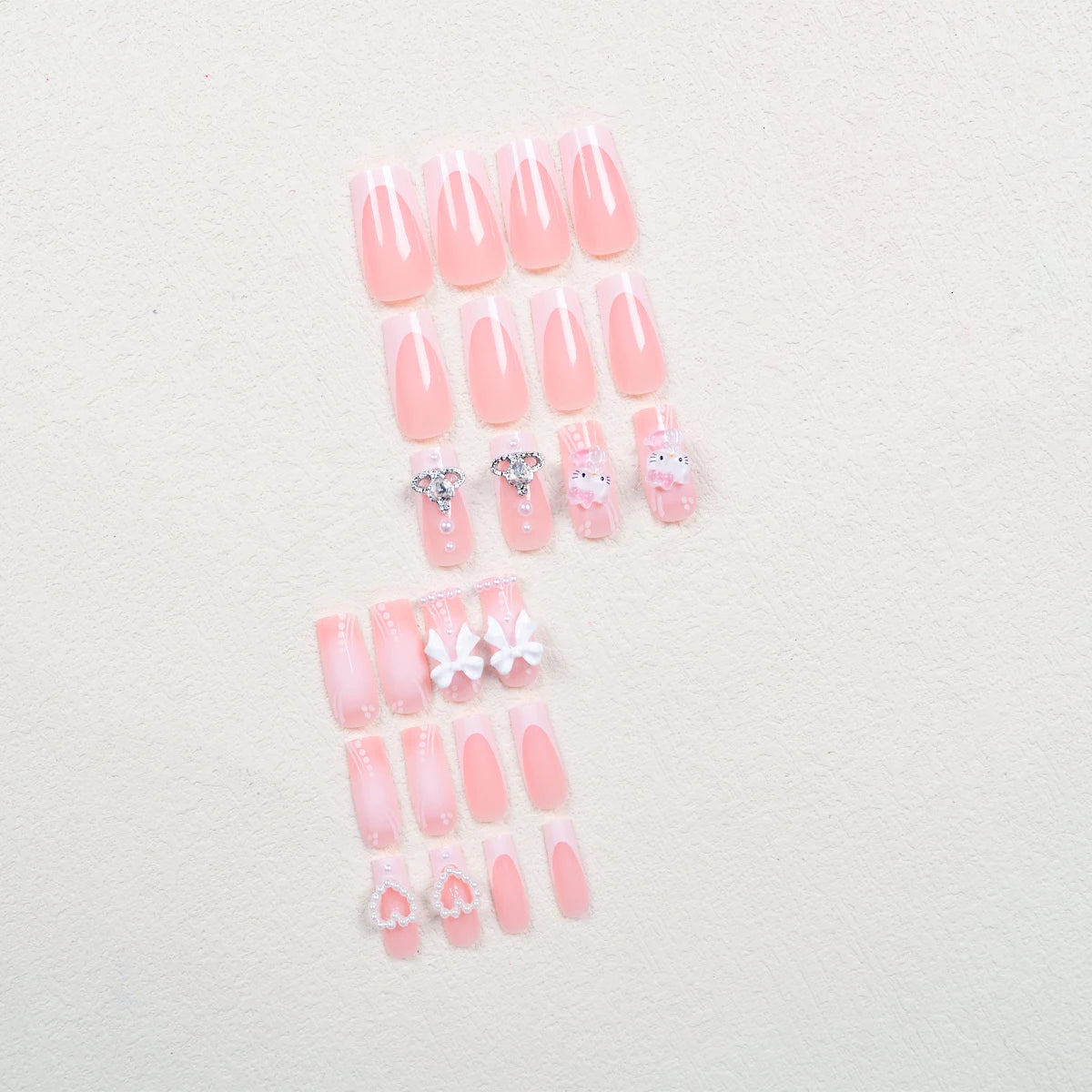Set of pink press-on nails with decorative elements on a light background
