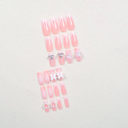 Set of pink press-on nails with decorative elements on a light background