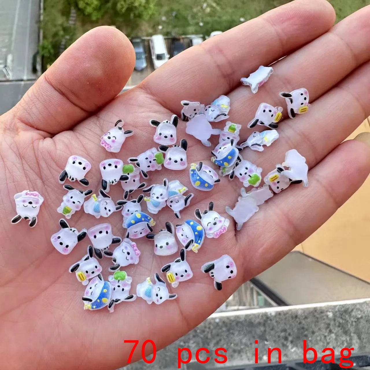 Hand holding a small collection of cartoon cow charms with text '70 pcs in bag'.
