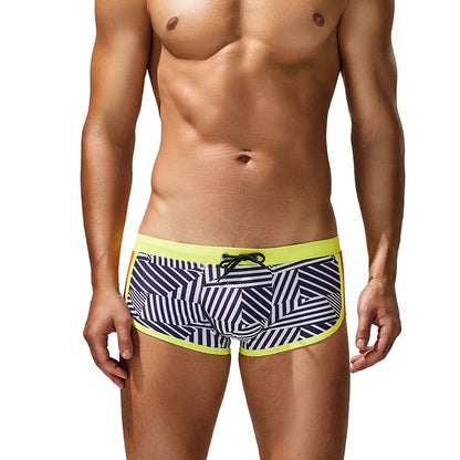 Man wearing a patterned swim shorts with yellow trim on a white background
